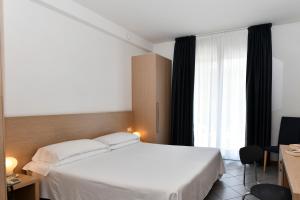 una camera d'albergo con un letto bianco e una finestra di Hotel Eden a Lido di Jesolo