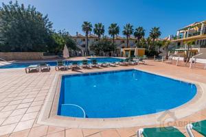 a swimming pool in a resort with chaises and chairs at Tavira Cocooning T1 by YHA in Tavira