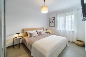 a white bedroom with a large bed and a window at Apartman A`Mare in Postira