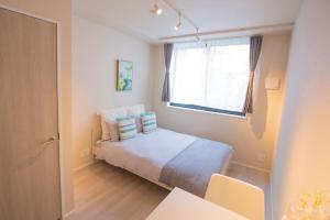 een kleine slaapkamer met een bed en een raam bij Your best choice for travel in Yoyogi EoY6 in Tokyo