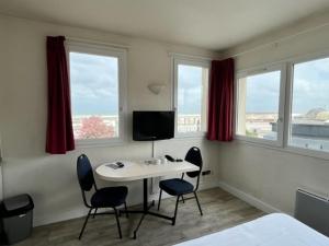 sypialnia ze stołem, 2 krzesłami i telewizorem w obiekcie Hôtel Résidence du Golf w Calais