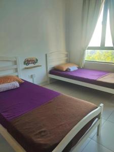 two beds sitting in a room with a window at TOP Muzaffar Homestay in Ayer Keroh