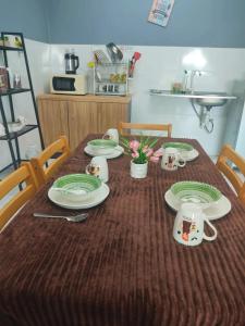 a table with plates and cups on top of it at TOP Muzaffar Homestay in Ayer Keroh