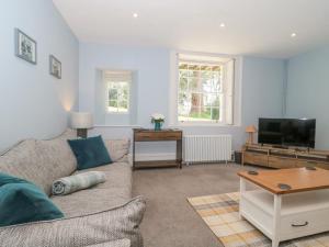 a living room with a couch and a tv at The Garden Flat in Bridport