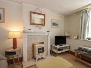 uma sala de estar com lareira e televisão em Lavender Cottage em Lyme Regis
