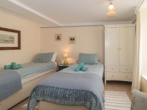 um quarto com 2 camas individuais e lençóis azuis em Lavender Cottage em Lyme Regis
