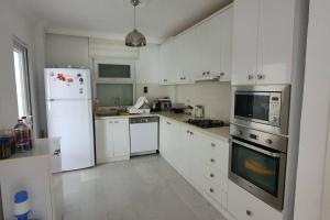 uma cozinha com electrodomésticos brancos e armários brancos em MAGNIFICENT VIEW with Private Pool & Piano, 3 Bedroom Villa, MIN 4 nigths em Gundogan