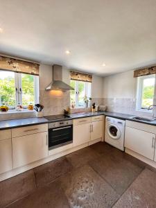 a kitchen with white cabinets and a washer and dryer at The Old Chapel in Axminster