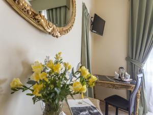 eine Vase gelber Blumen auf einem Tisch mit einem Spiegel in der Unterkunft Hotel Regina Giovanna in Rom