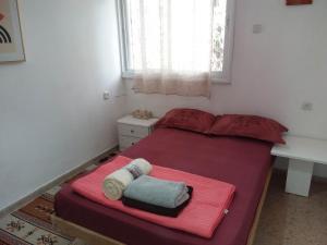 a small bedroom with a red bed with a window at דירת 80 מ"ר למשפחה או זוג in Qiryat Bialik +5 photos