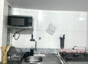 a kitchen with a sink and a microwave at Casa top aeroporto in Macaé +6 photos