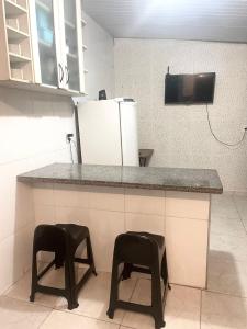uma cozinha com dois bancos num balcão com um frigorífico em Casa top aeroporto em Macaé