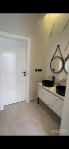 a white bathroom with a sink and a mirror at شاليهات أبيات الفندقية in Al Baha