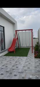 einen Spielplatz mit einer roten Rutsche auf einer Terrasse in der Unterkunft شاليهات أبيات الفندقية in Al Bahah