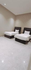 dwa łóżka w pokoju z białymi ścianami w obiekcie شاليهات أبيات الفندقية w mieście Al-Baha