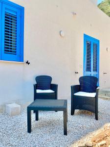 two chairs and a table in front of a building at Bilocale Vista Mare in Marettimo