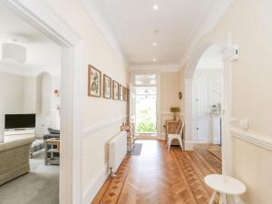 un soggiorno con pareti bianche e un corridoio con pavimenti in legno di The Westgate a Bridport