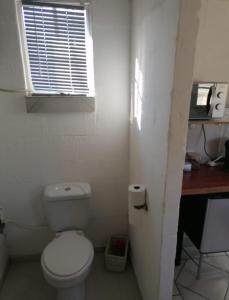 a bathroom with a toilet and a desk and a window at Hoenerhok in Vanrhynsdorp