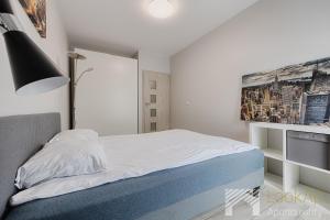 a white bedroom with a bed and a tv at Primo V by LookAp in Łódź