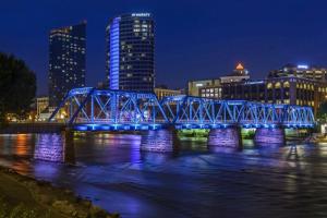 a blue bridge over a river in a city at night at Luxury 2BR Penthouse in Downtown GR in Grand Rapids
