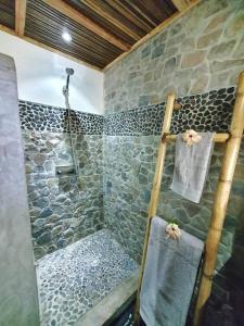 a bathroom with a shower with a stone wall at Villa Ilo Komba in Nosy Komba