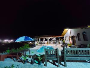 - une piscine de nuit avec des chaises et un parasol bleu dans l'établissement Pousada Pé na Montanha, à Socorro