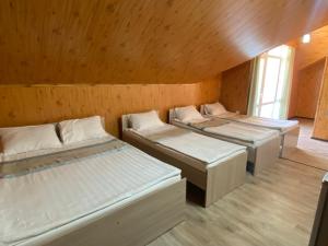 three beds in a room with wooden walls at Eram Garden Hotel in Bosteri