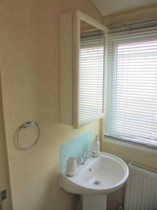 a bathroom with a white sink and a window at The Grange: Solstice:- 6 berth, enclosed veranda in Ingoldmells