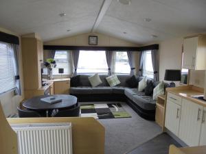 a living room with a couch and a table at The Grange: Solstice:- 6 berth, enclosed veranda in Ingoldmells