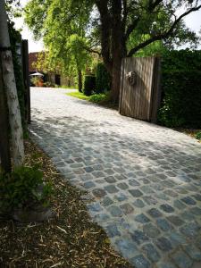 ルッデルフォールデにあるCasa Leone near Bruges with jacuzzi & parkingの木門と柵の石畳道