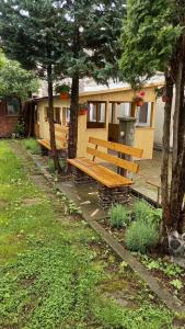 a wooden bench in front of a building with trees at CASA CU LAVANDĂ in Vatra Dornei
