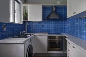 a blue tiled kitchen with a sink and a dishwasher at Chic designer home next - Hilton in Athens +11 photos
