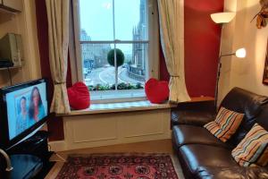sala de estar con sofá y ventana con almohadas rojas en Royal Mile apt, just 1 min from Edinburgh Castle!, en Edimburgo