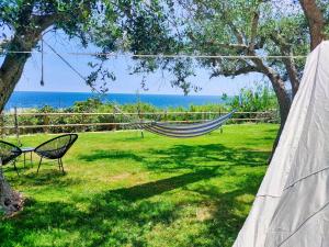 a hammock in a yard with a view of the ocean at La Tenda a Marina Serra di Casa Camilla Journey in Marina Serra