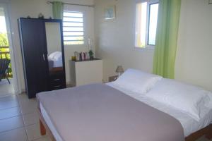 Schlafzimmer mit einem weißen Bett und einem Spiegel in der Unterkunft LE BIGARADIER in Sainte-Rose