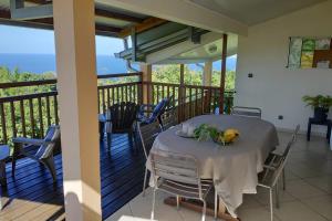 a table on a balcony with a view of the ocean at Villa Bigaradier - Meublé 3 étoiles avec vue mer sur la côte Est in Sainte-Rose