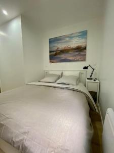 Appartement T2 plein centre de Bray sur Seine في Bray-sur-Seine: سرير أبيض في غرفة نوم مع لوحة على الحائط