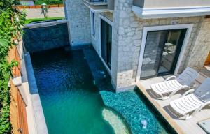 an image of a pool with chairs and water at Dalyan Central 4 Bedroom Ensuite Private Villa with Swimming Pool in Dalyan
