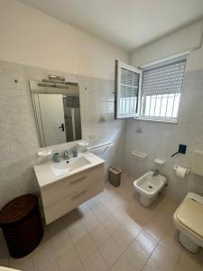 bagno con lavandino, servizi igienici e specchio di Monte Rosa Apartments a Torre San Giovanni Ugento