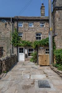 an old stone house with a white door at Chapel Cottage with Log Burner (Dog Friendly) in Hawes