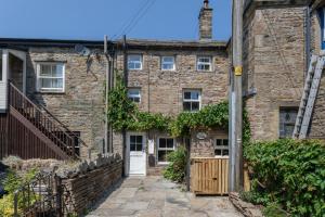 an old brick house with a white door at Chapel Cottage with Log Burner (Dog Friendly) in Hawes
