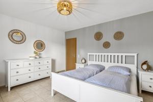 a bedroom with a white bed and white dressers at Strand Quartier in Timmendorfer Strand