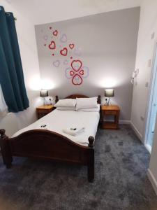 グレート・ヤーマスにあるCavendish House Hotelのベッドルーム1室(白いシーツと赤い蝶が壁に飾られたベッド1台付)