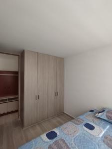 een slaapkamer met een bed en houten kasten bij Lindo Apartamento Ibagué-Tolima in Ibagué