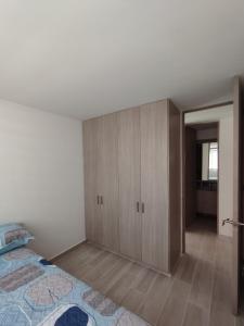 een slaapkamer met een bed en een houten kast bij Lindo Apartamento Ibagué-Tolima in Ibagué