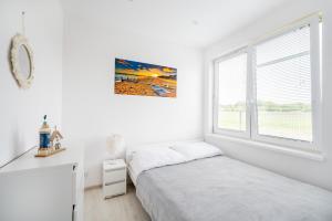 a white bedroom with a bed and a window at Niebiańska Przystań Rusinowo in Rusinowo