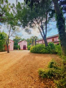een grote tuin met bomen en een roze gebouw bij Casal Camillo in Case Selva Grande