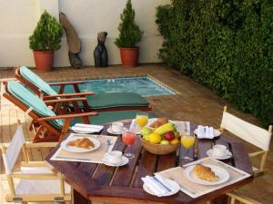 Una mesa con comida y fruta con una piscina. en Esperanza Guest House, en Ciudad del Cabo