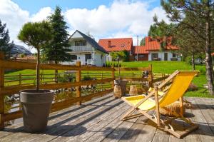 une chaise jaune assise sur une terrasse en bois dans l'établissement Domki Nad Potokiem574067621, à Ustrzyki Dolne