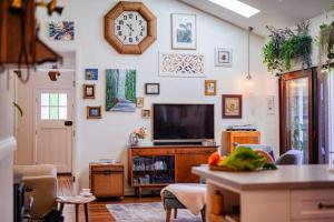 a living room with a tv and a clock on the wall at The Rustic Cottage - Canungra in Canungra